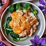 Thai chicken rama on a plate over rice, spinach and broccoli.