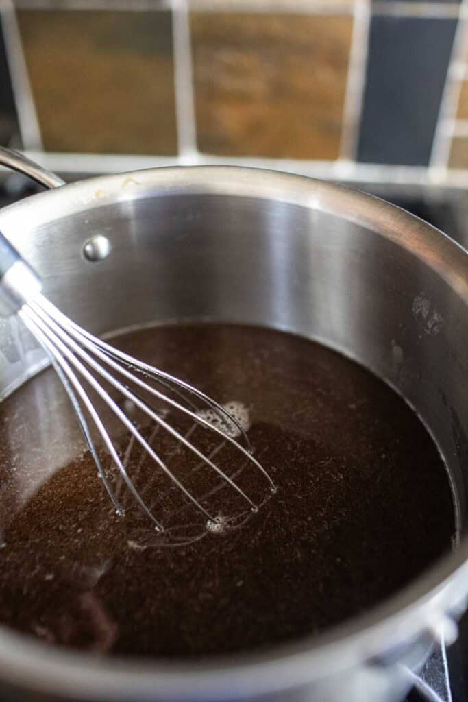 Tamarind tea in a pot with a whisk.