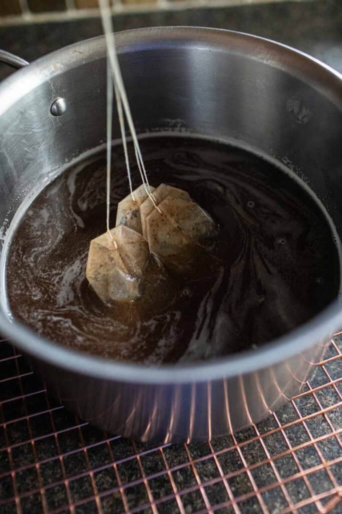 Tea bags in a stock pot with tamarind paste. 