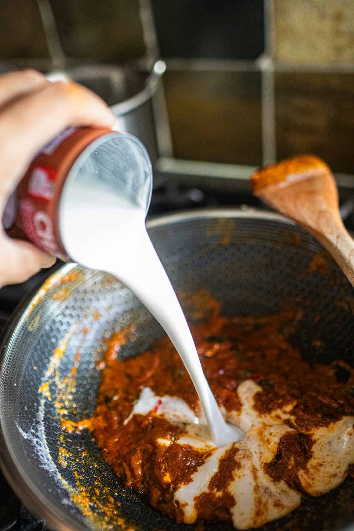 Coconut milk pouring into a wok.