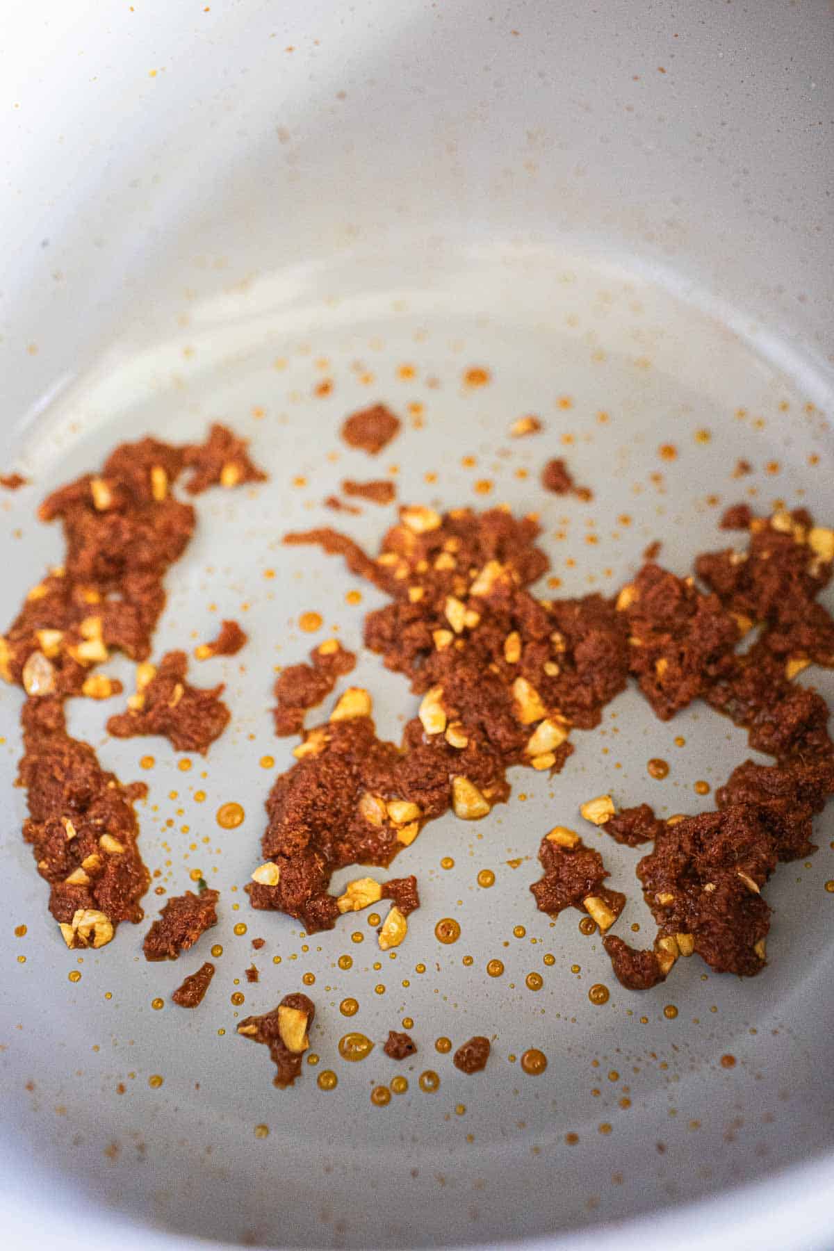 Red  curry paste frying with garlic in a  pot.