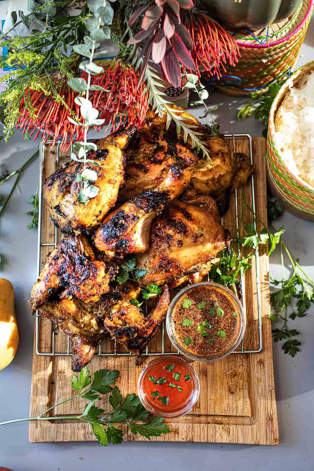 Thai Gai Yang  on a cutting board with dipping sauce. 