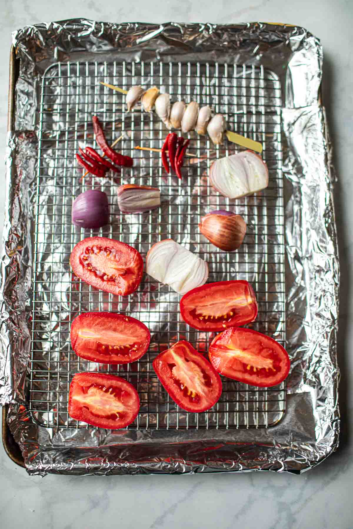 Tomato, shallot, garlic and chili on a rack.