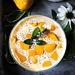 Mango sago in glass with mango slices on top.