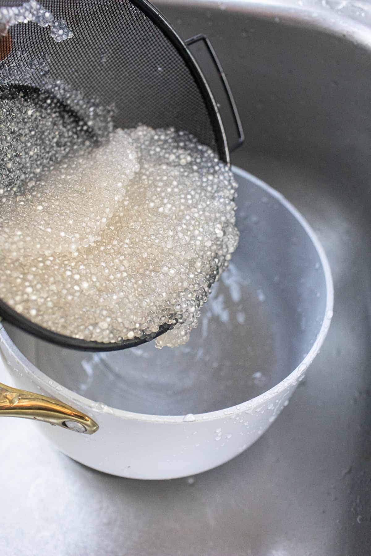 Pouring cooked Mini tapioca pearls into a pot.  