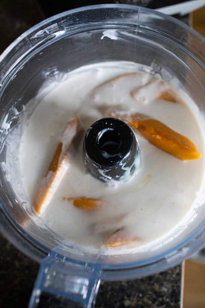 Mango slices and milk in a food processor.