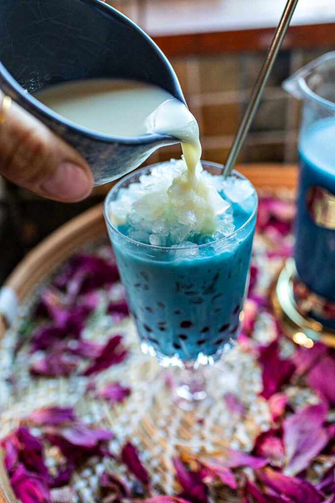 Milk pouring int blue tea boba glass. 