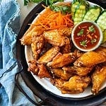 Thai chicken wings on a platter with sauce.