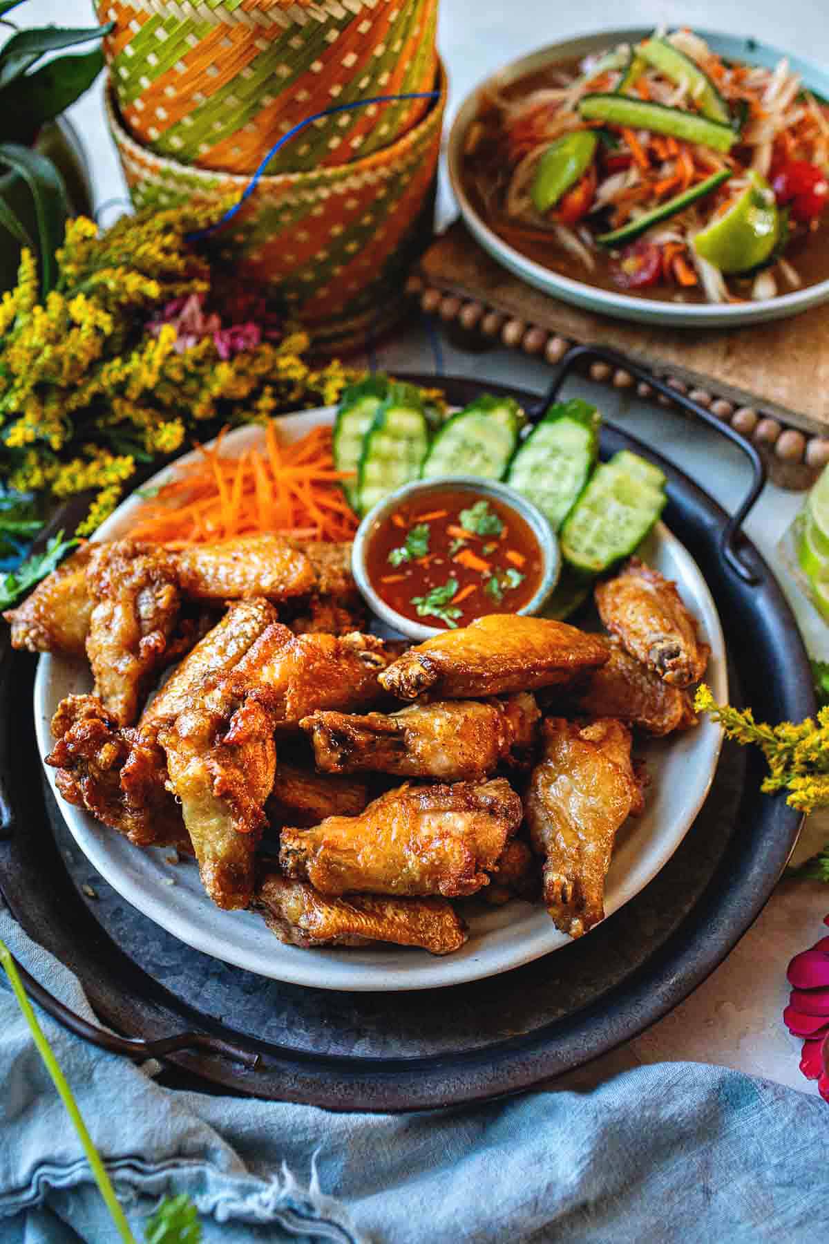 Thai chicken wings on a platter with chili sauce. 