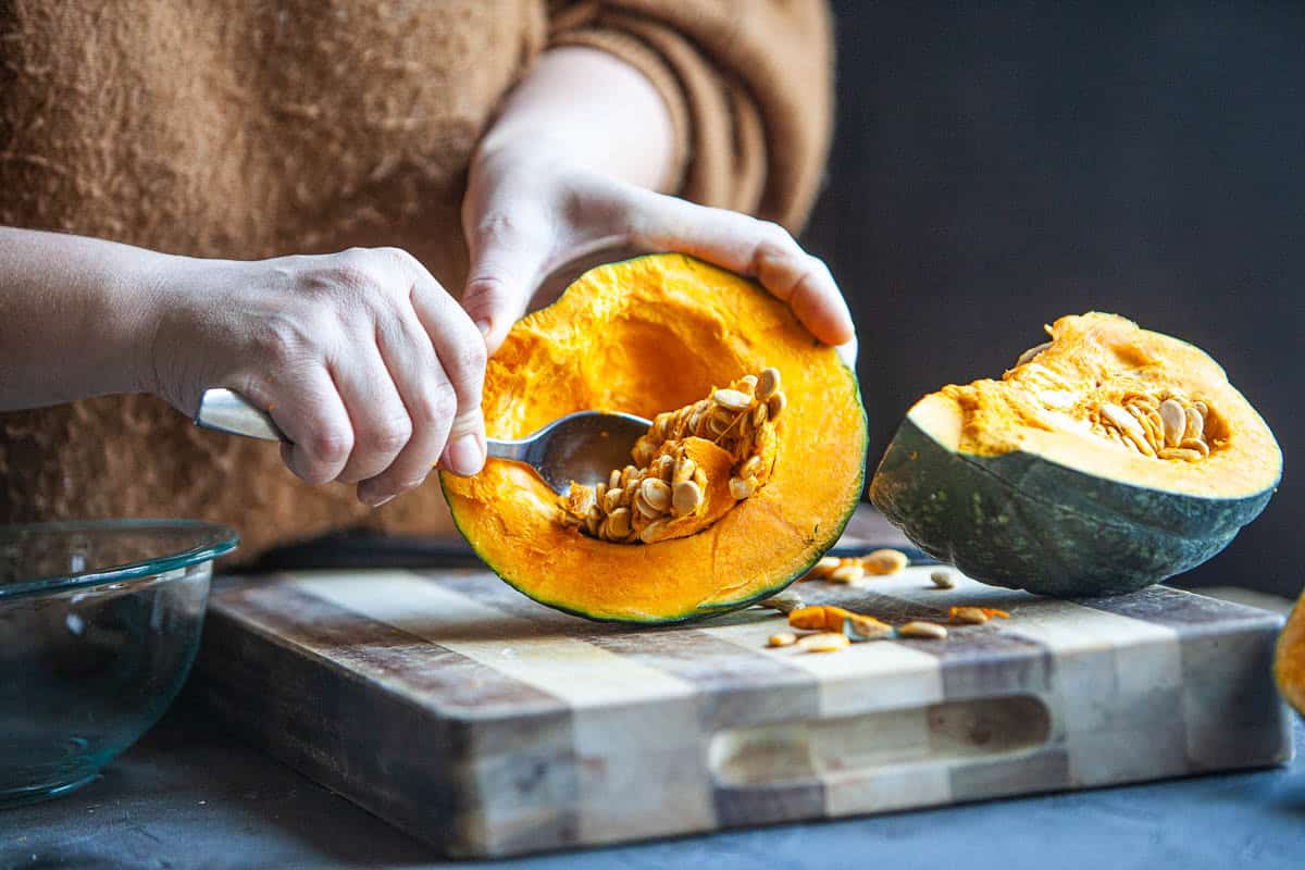 Spoon scooping out kabocha squash on the table. 