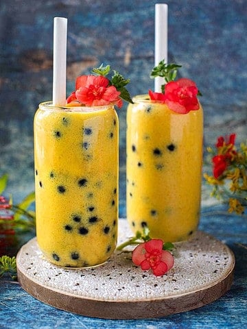 Mango boba tea in glassses on a board.