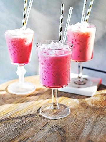 Thai pink drink in 3 glasses on a table.