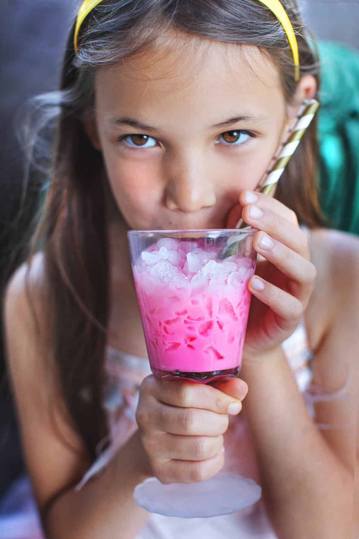 Cute girl drinking Thai Nom Yen Pink Drink in a glass. (;