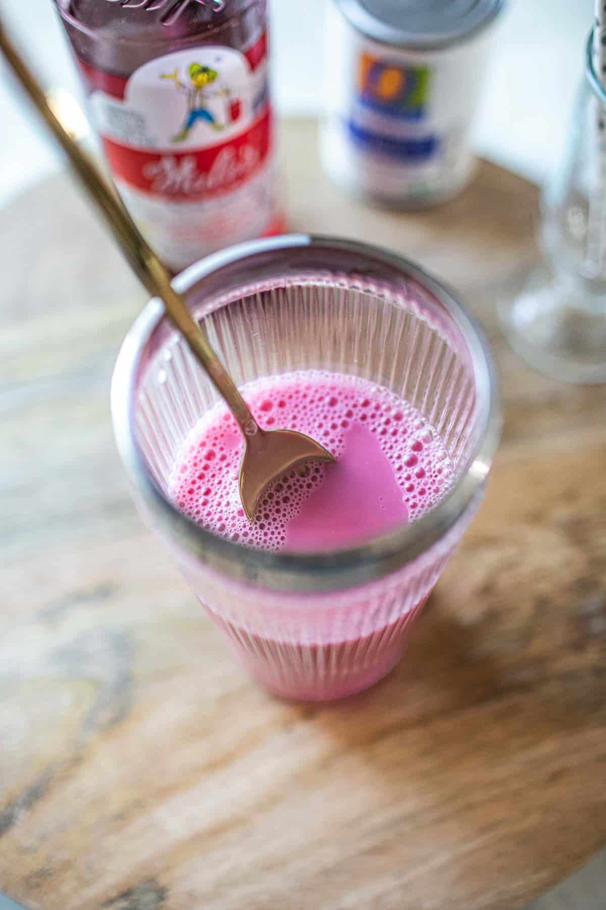 Thai pink drink in a glass with a spoon. 