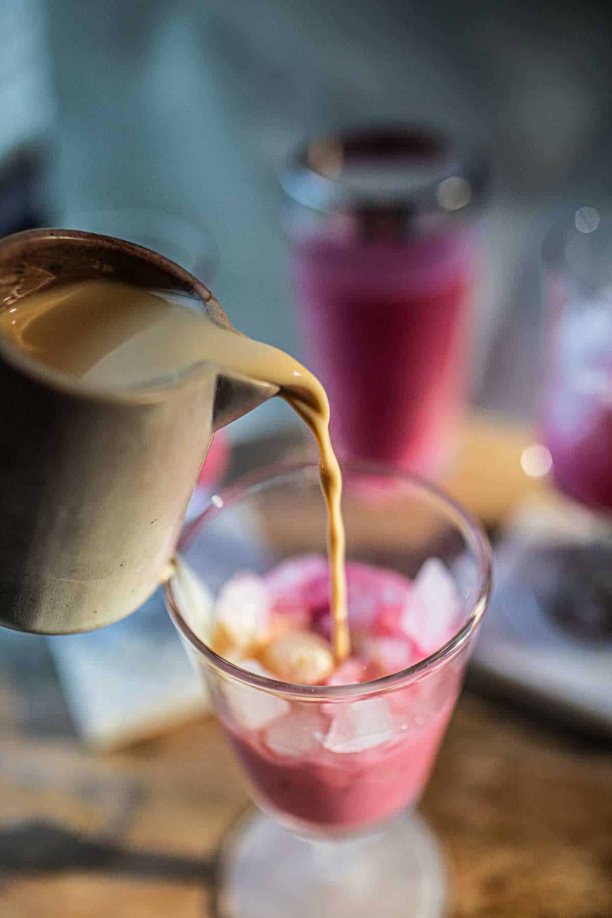 Evaporated milk pouring into Thai pink milk Nom Yen.