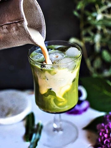 Evaporated milk pouring into green tea.