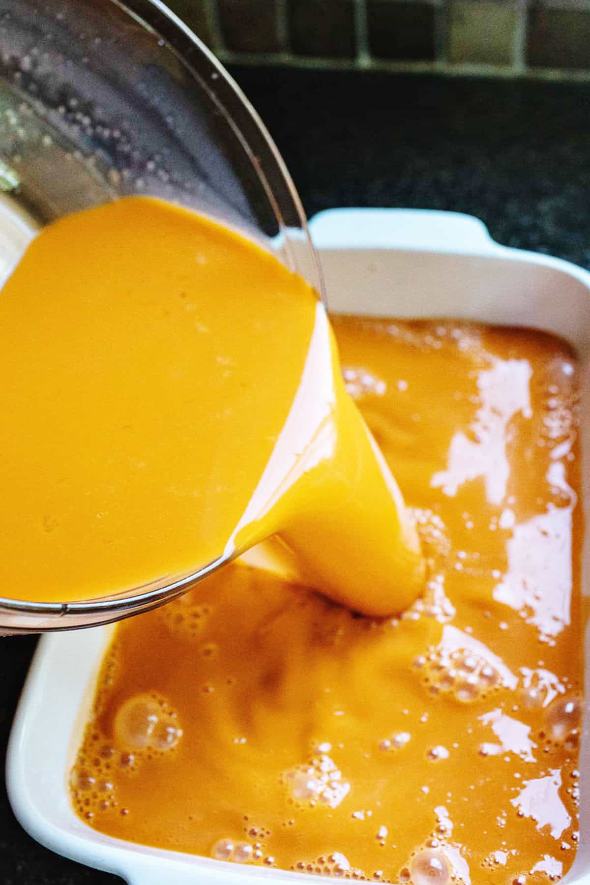 Thai tea pouring into a deep dish pan. 