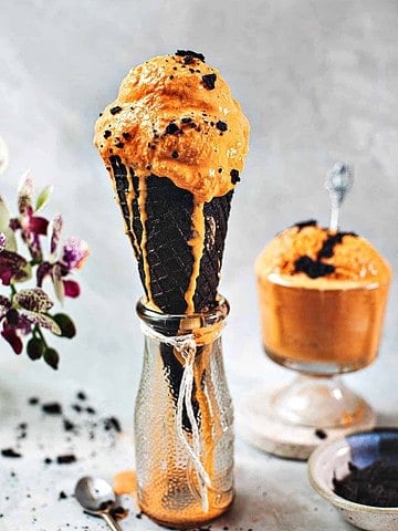 Thai tea ice cream in a cone over a vase.