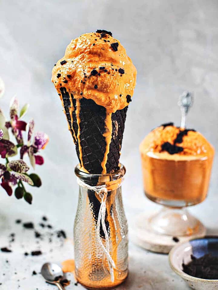Thai tea ice cream in a cone over a vase.