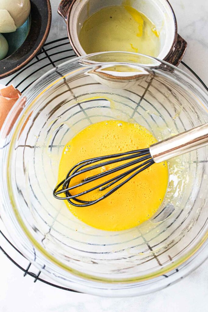 Egg yolks in a bowl with a whisk. 
