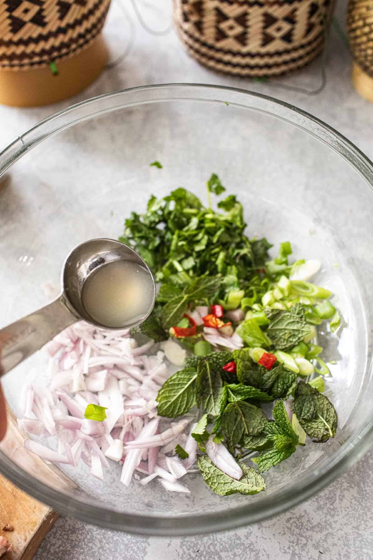 Lime juice poring into a bowl of salad.