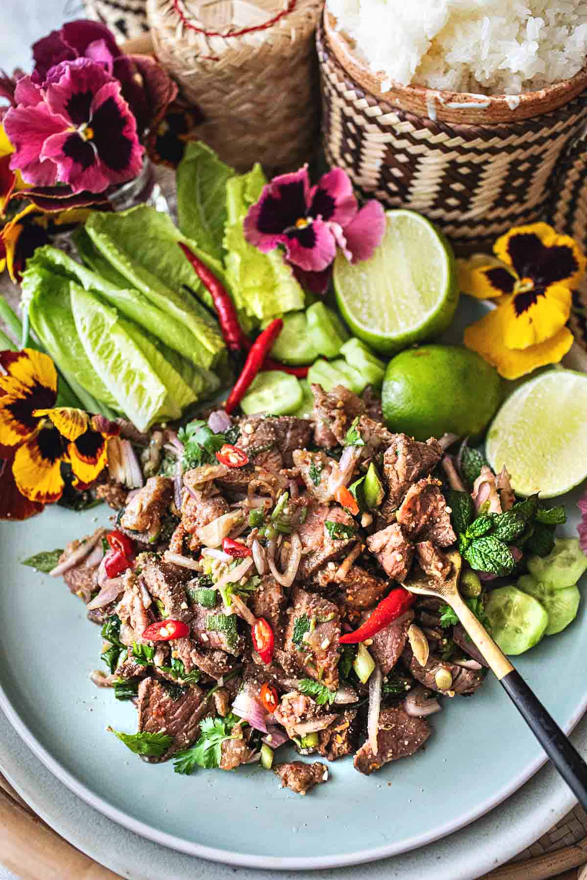 a fork digging into beef larb on a plate. 