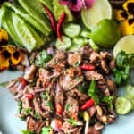 Beef larb on plate with veggies and garnishes.