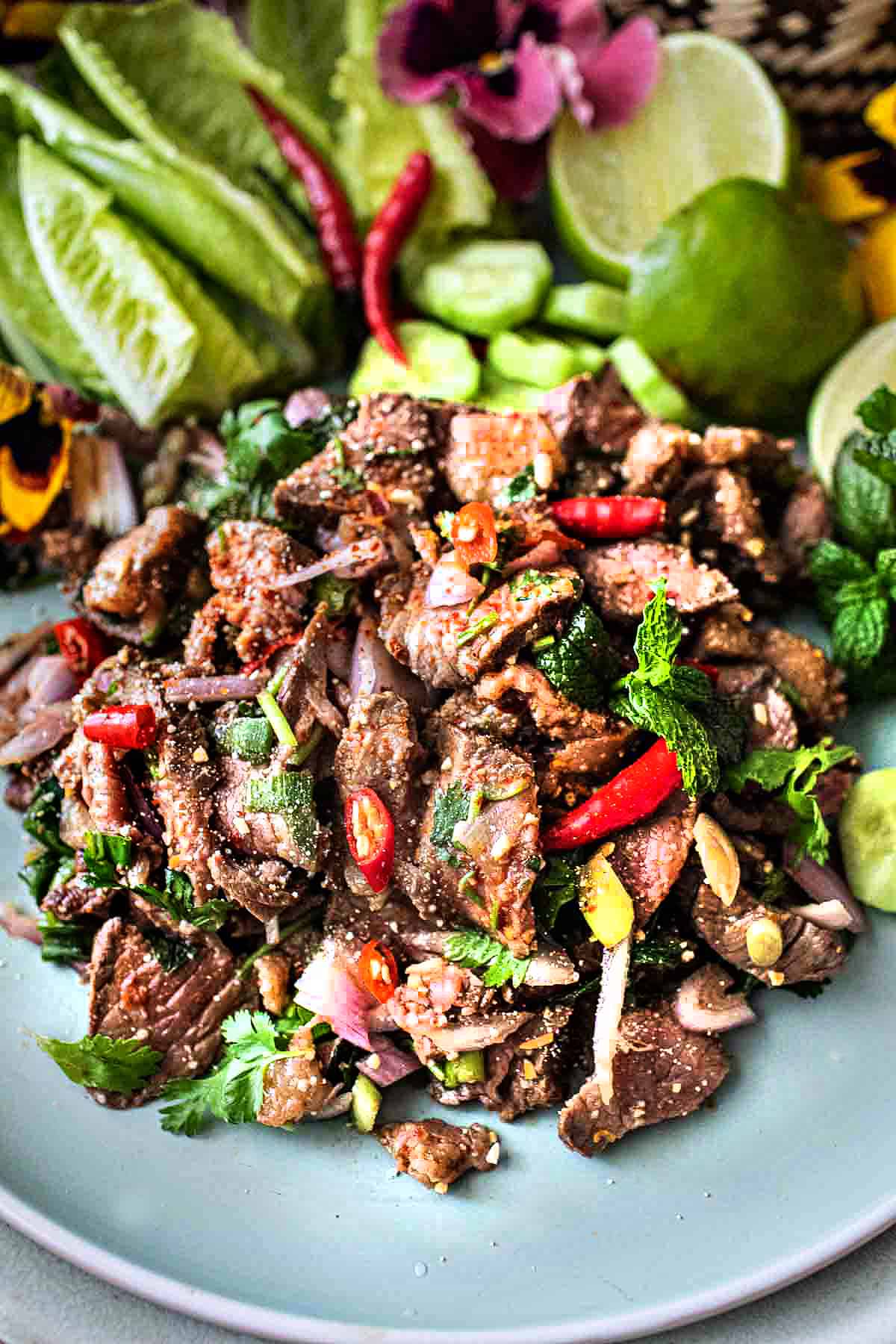 Beef larb on a platter with garnishes.