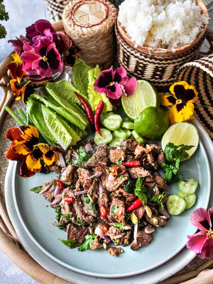 Beef Laab on a plate with lettuce, lime and cucumber slices.