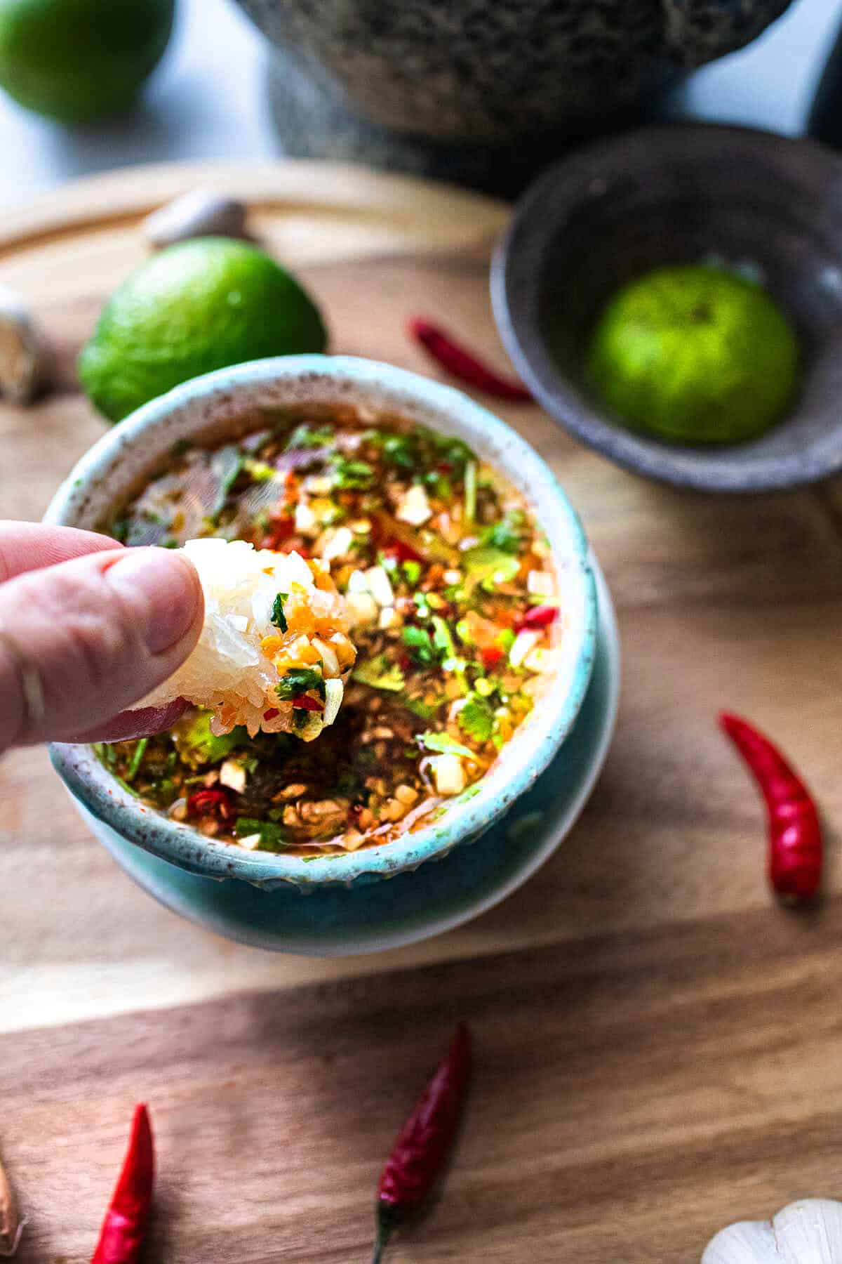 finger dipping sticky rice in Lao Jeow Som sauce.