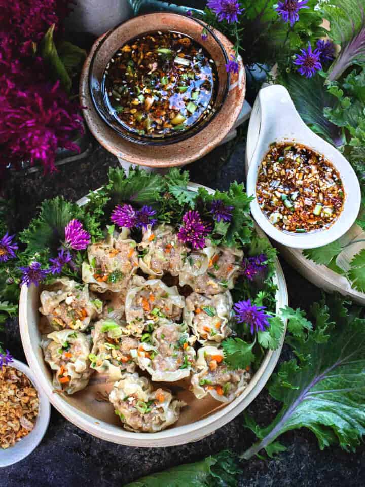 Kanom Jeeb Thai dumplings on a platter with sauces.