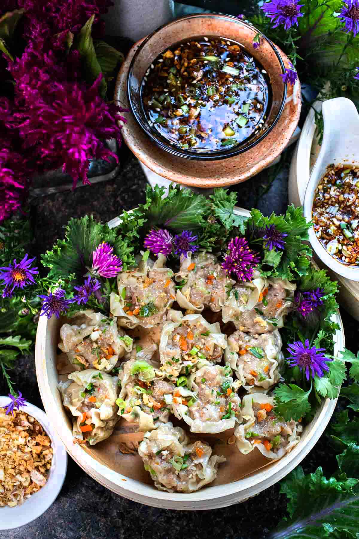 Kanom Jeeb dumplings in a serving plate with sauce.