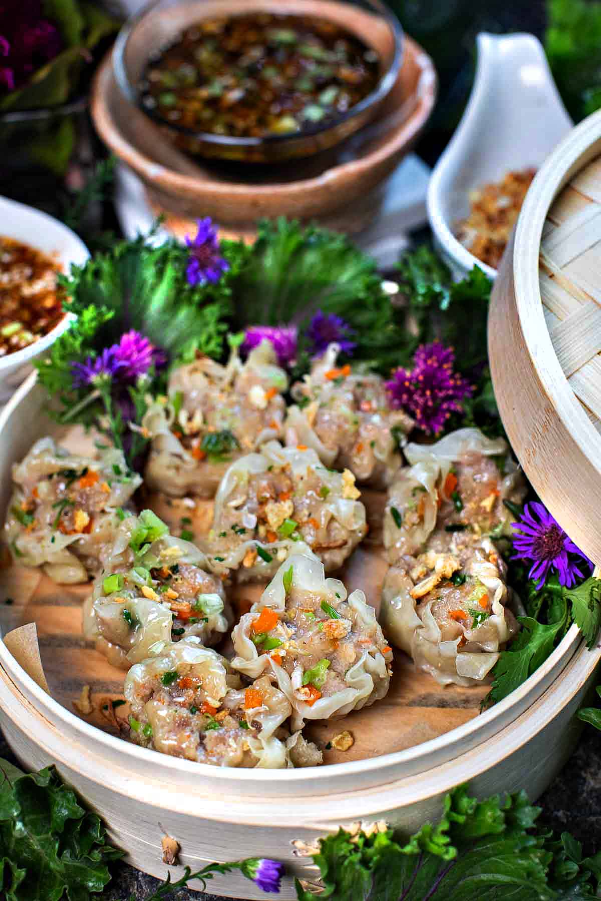 Kanom Jeeb dumplings on a steamer with sauce. 