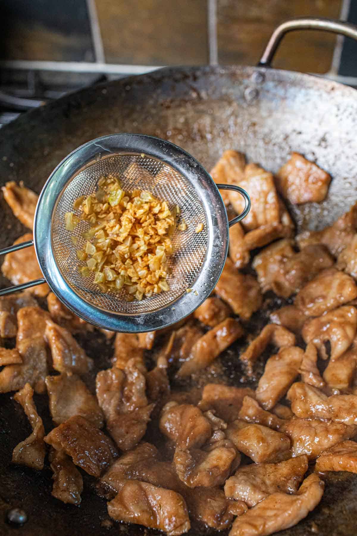 Crispy garlic pouring over seared pork 