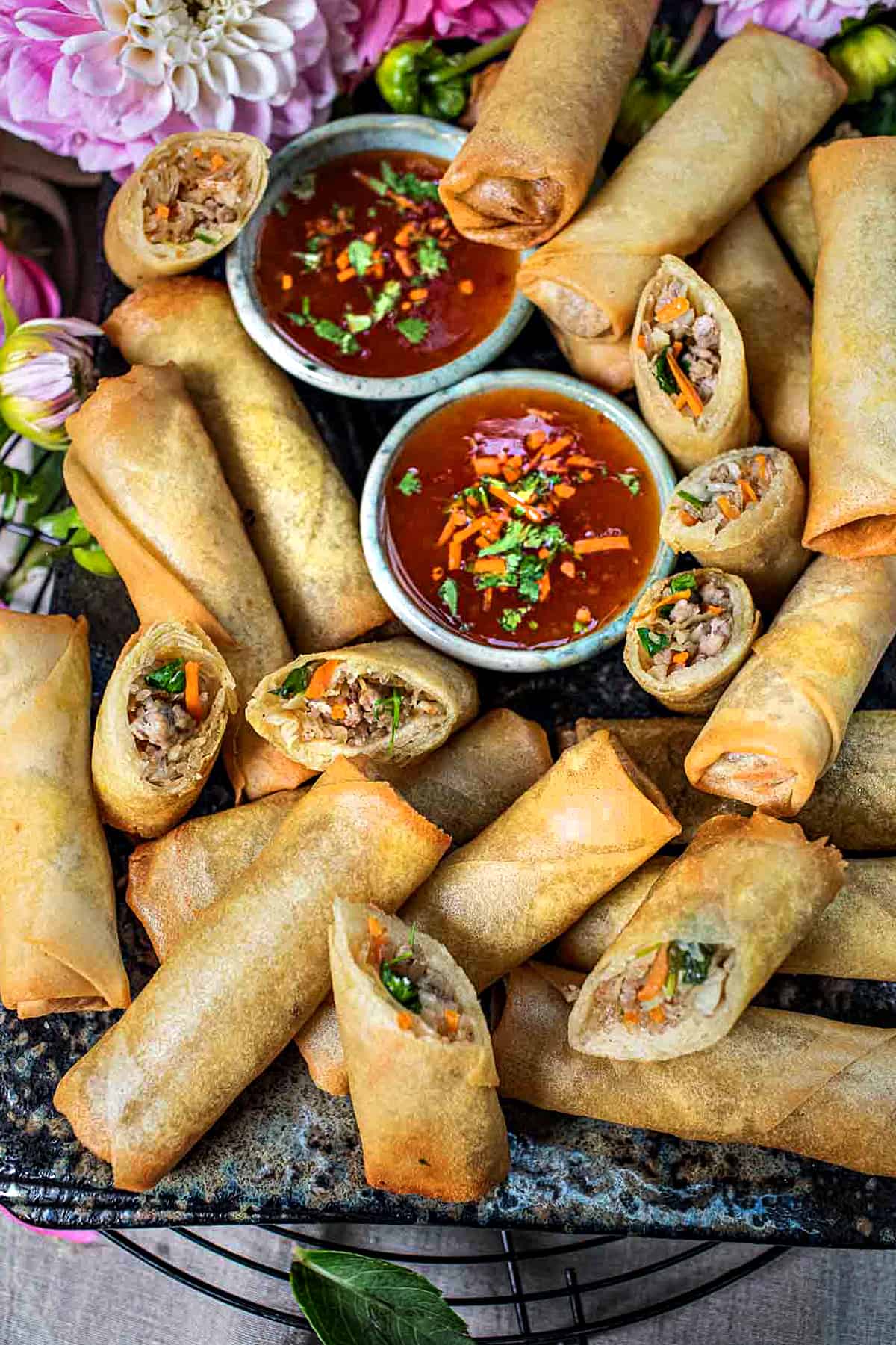 Thai egg rolls on a platter with dipping sauce.