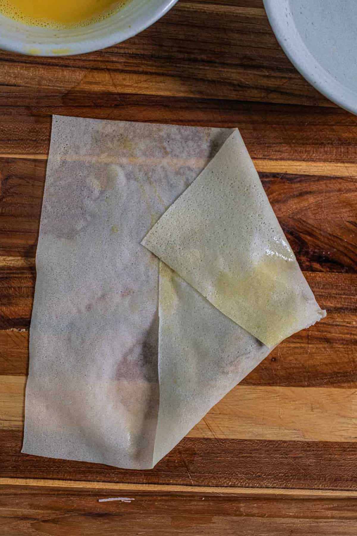 A partially wrapped egg roll on a cutting board.