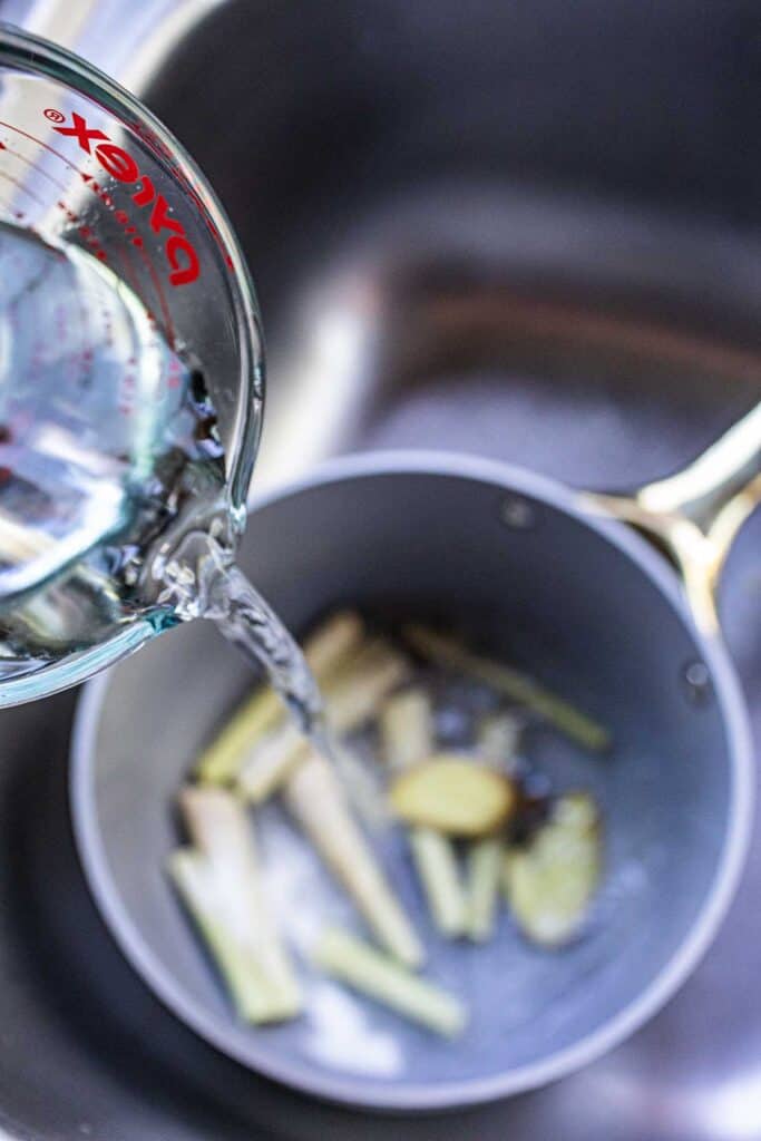 water pouring into Lemongrass ginger tea boiling in a pot. 