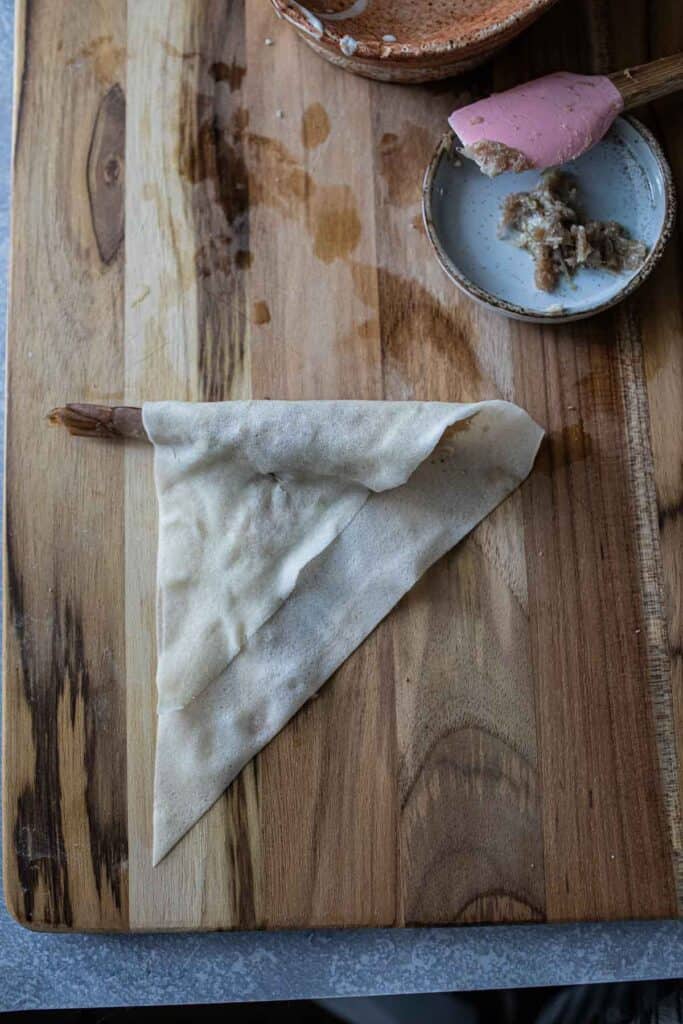 Partially rolled shrimp in a blanket on a cutting board. 