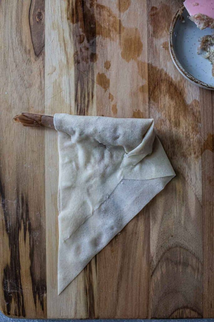 Half Rolled shrimp in a blanket on a cutting board. 