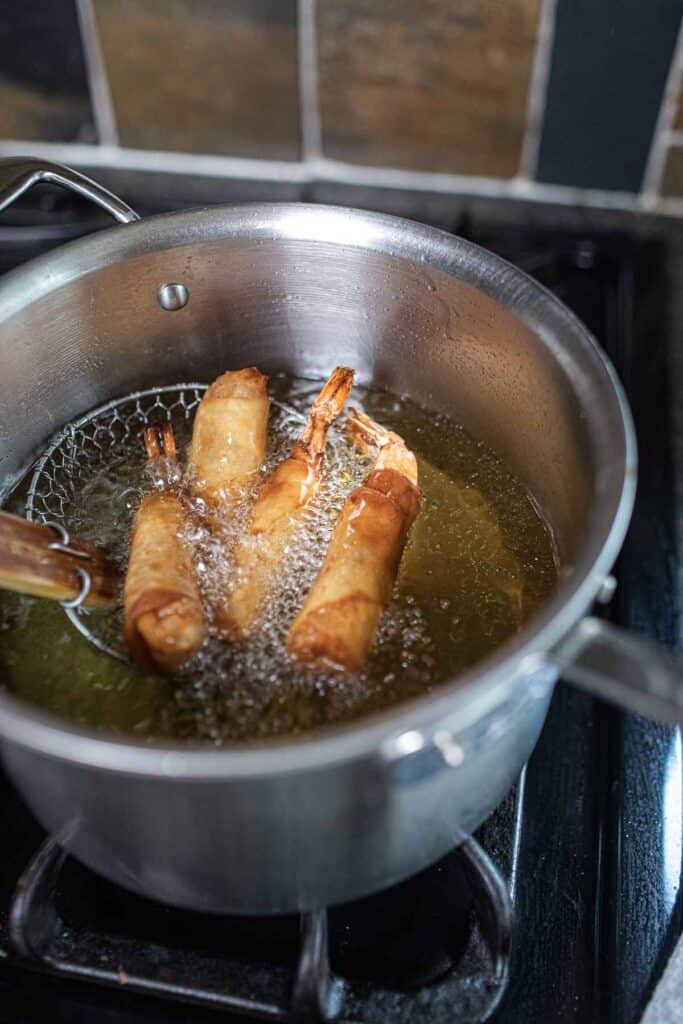 Shrimp rolls frying in hot oil.