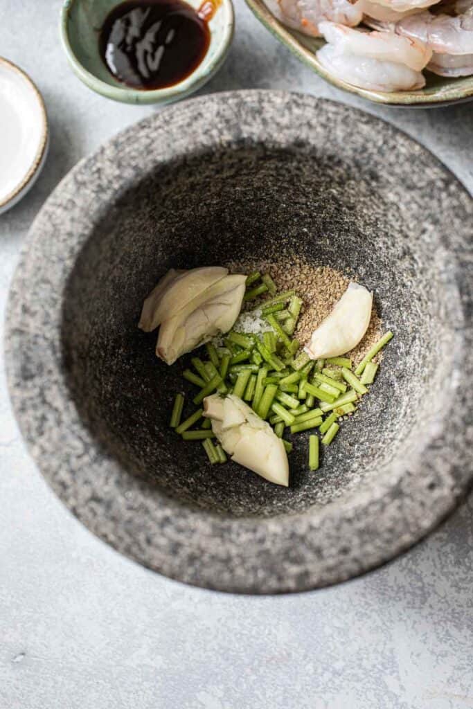 garlic, cilantro stems and pepper in a mortar and pestle.