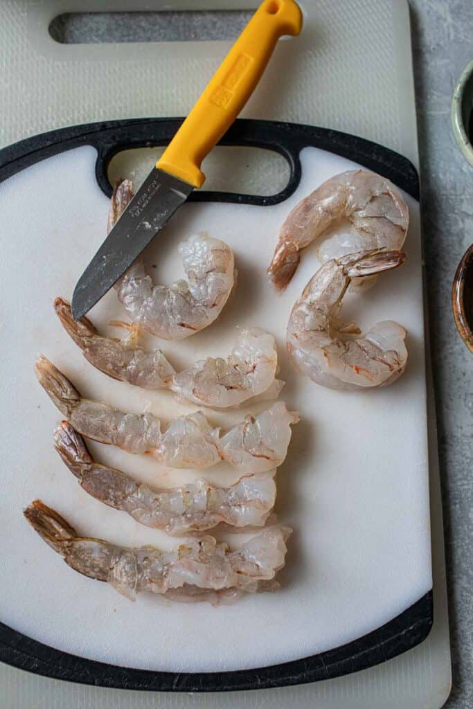 Raw Tiger shrimp on a cutting board with a knife. 