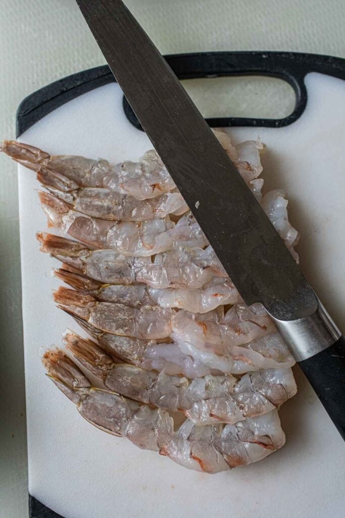 Tiger shrimp on a cutting board with a knife. 