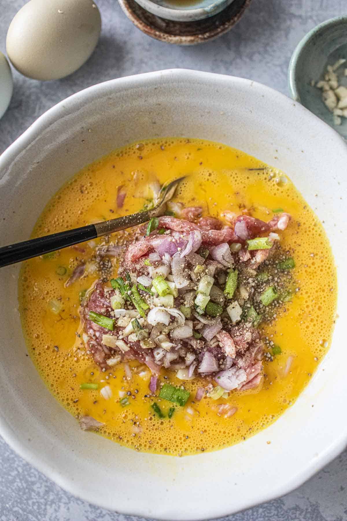 Thai minced pork omelette in a bowl with ground pork and herbs.  