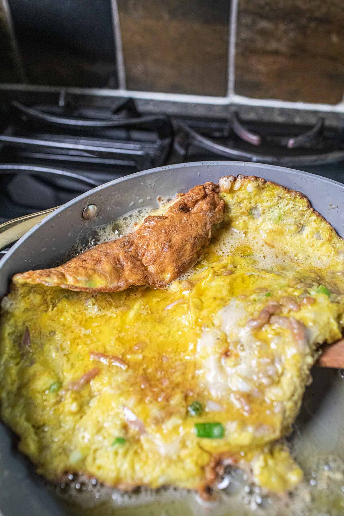 Frying omelette in a pan on the stove. 