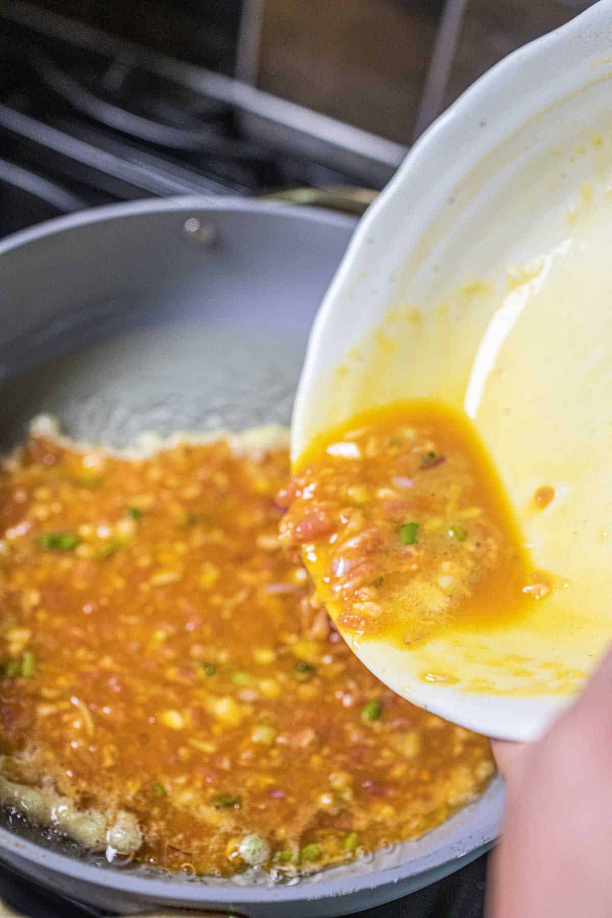 Omette pouring into a pan on the stove. 