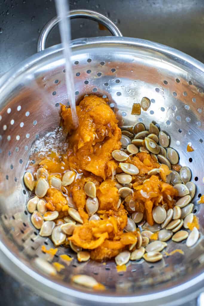 water running over Kabocha squash seeds in colander. 