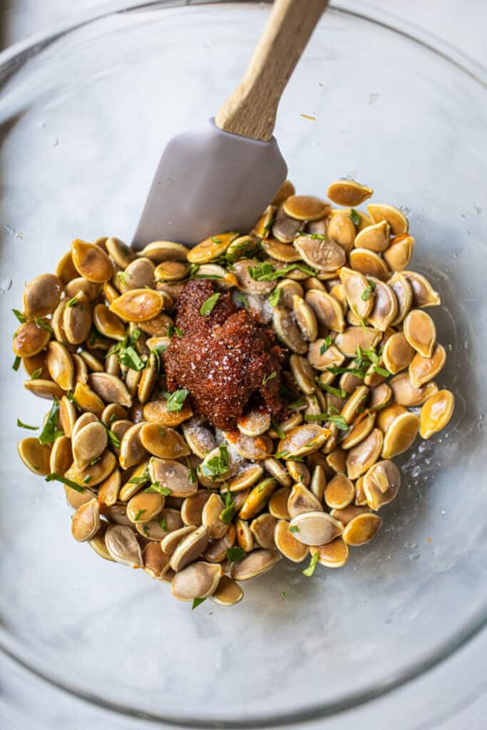 Roasted Pumpkin seeds with tom yum paste and herbs in a glass bowl. 