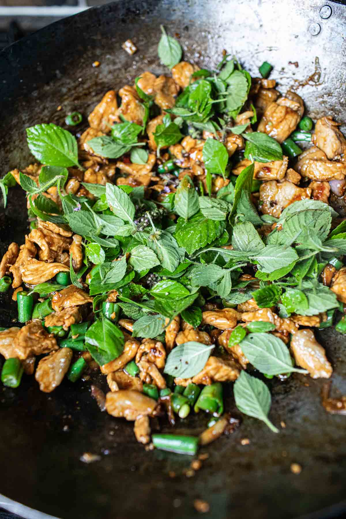 Holy basil in a wok with pork stir fry. 