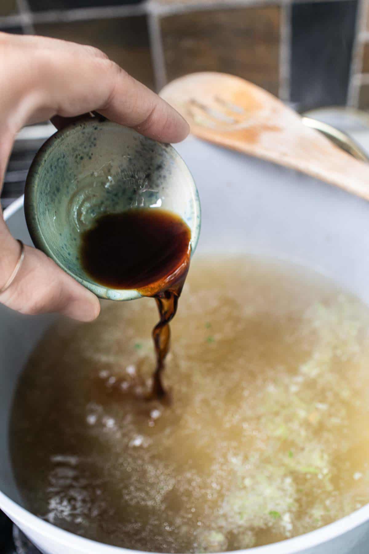 Sauce pouring into a pot of broth.